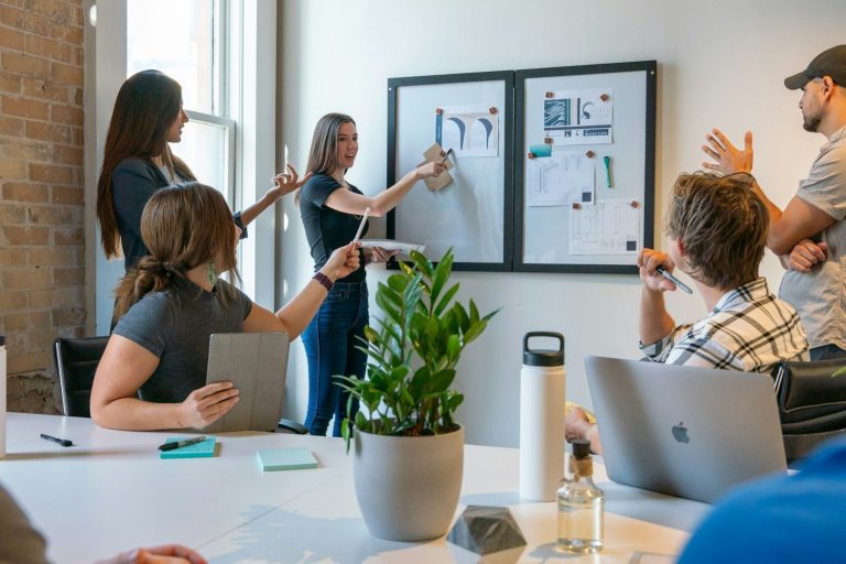 Ein Team diskutiert an einem Whiteboard mit Grafiken und Notizen in einem Konferenzraum.